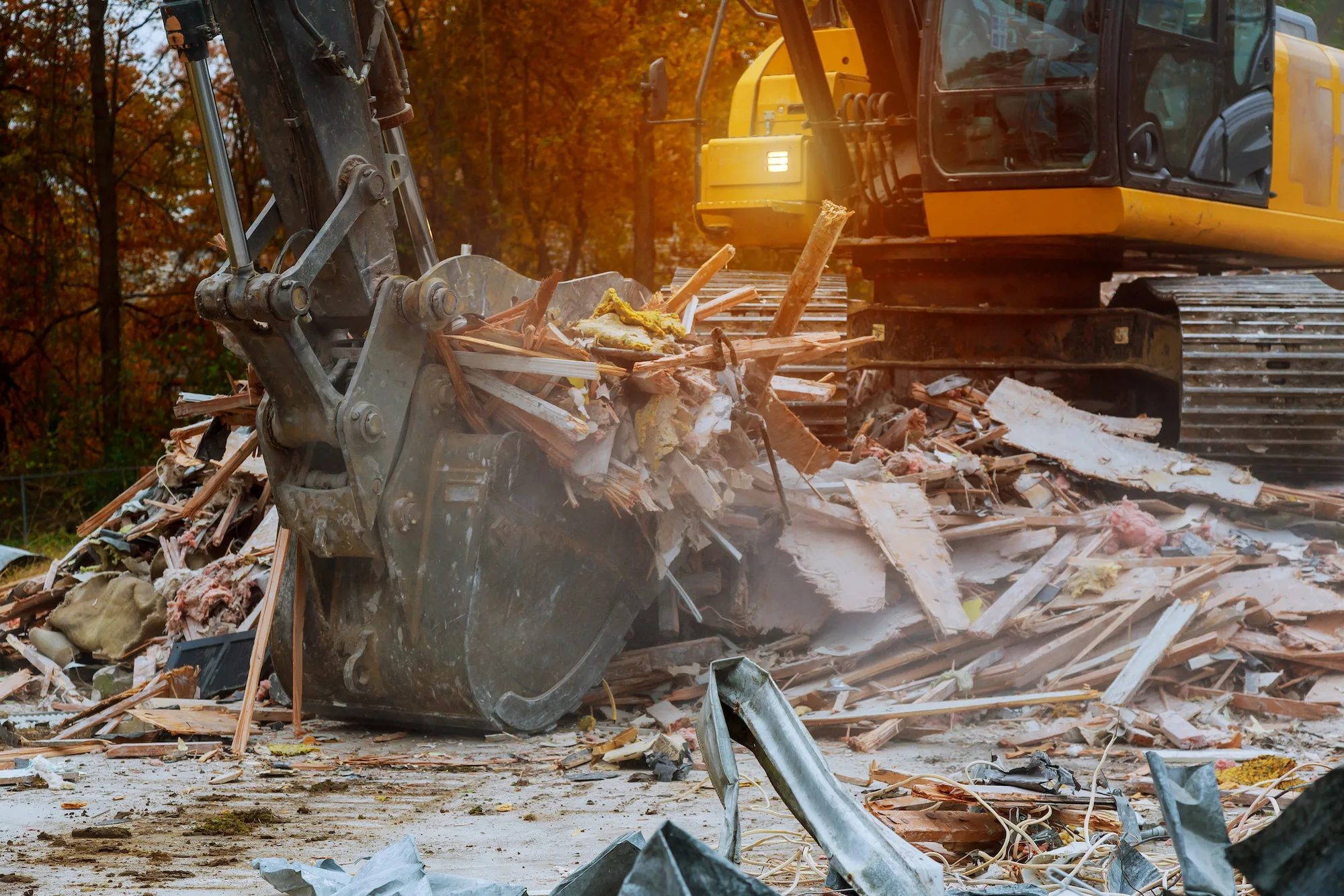 Excavator bucket sorting timber and debris from a demolished house