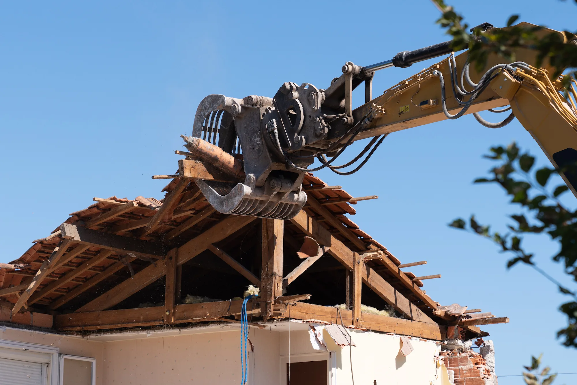 Excavator grab tearing the roof frame off a house