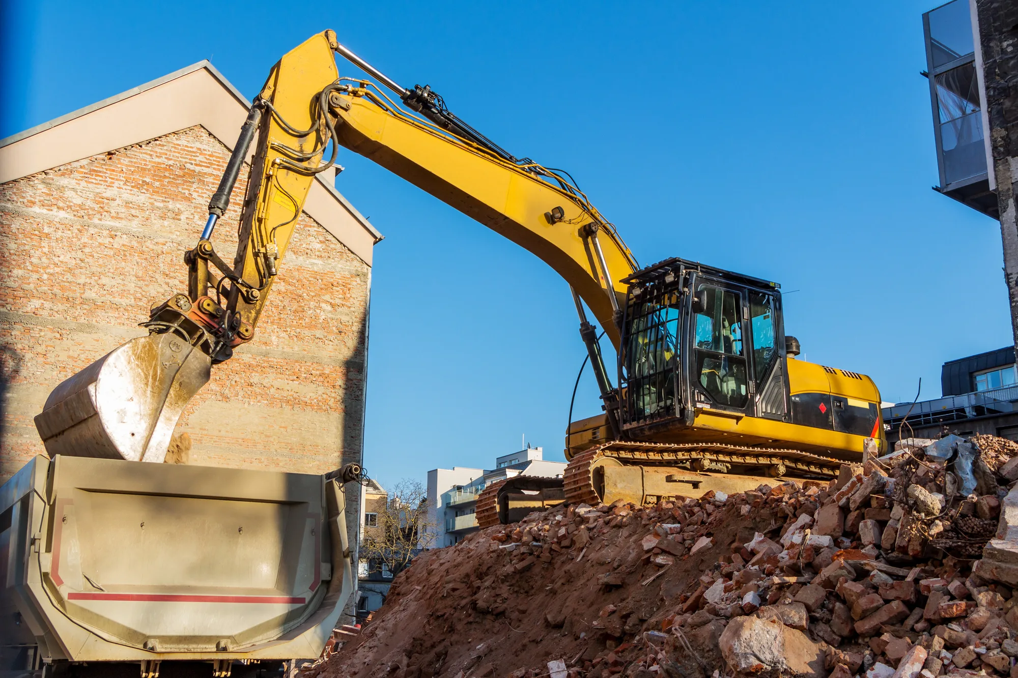 Excavator pulling down the brick walls of a house during a full house demolition