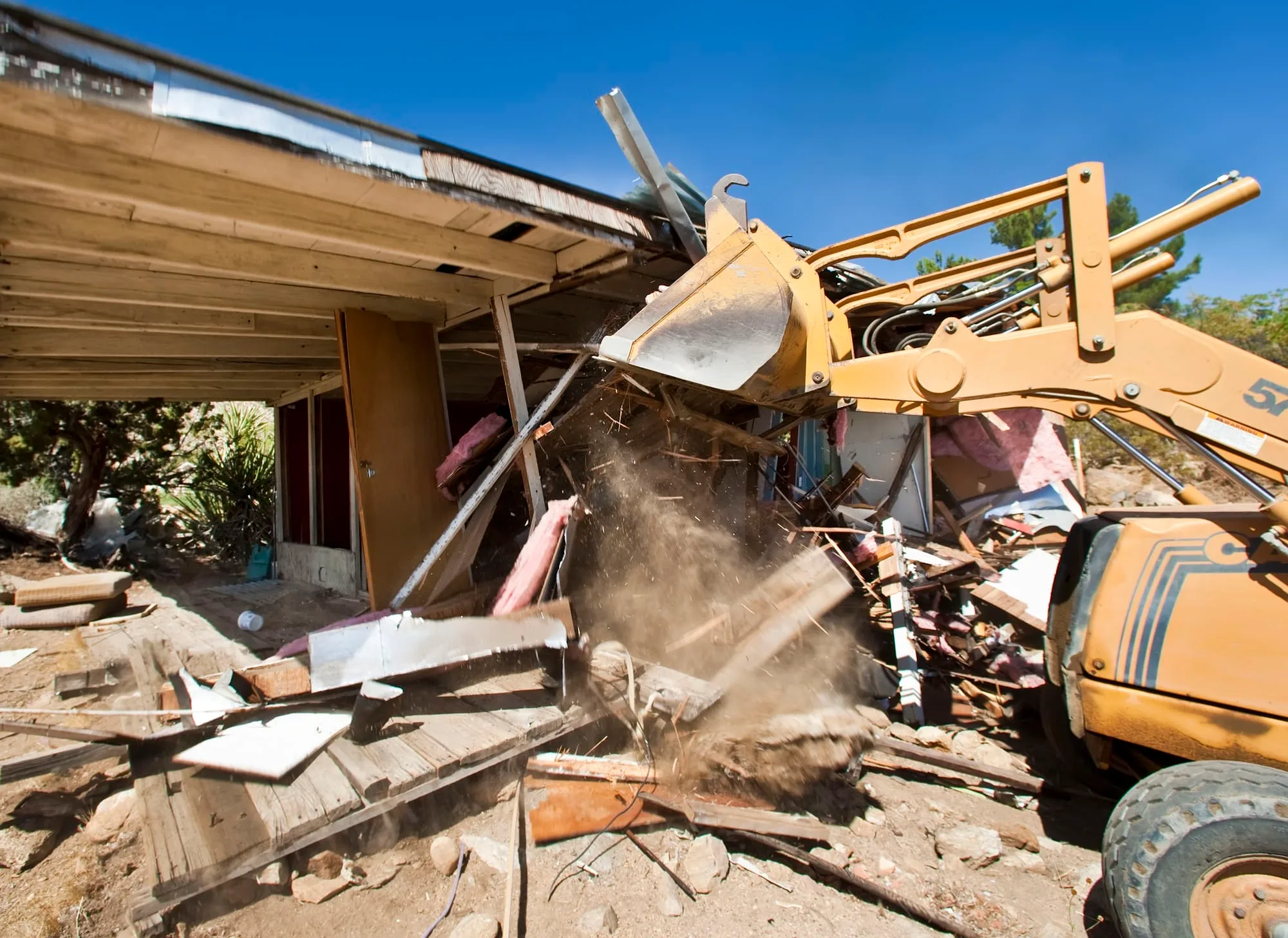 Excavator knocking down the front of a house