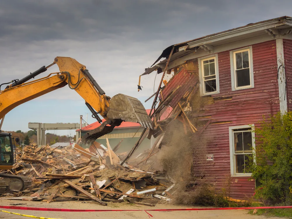 Excavator demolishing a two-storey timber house