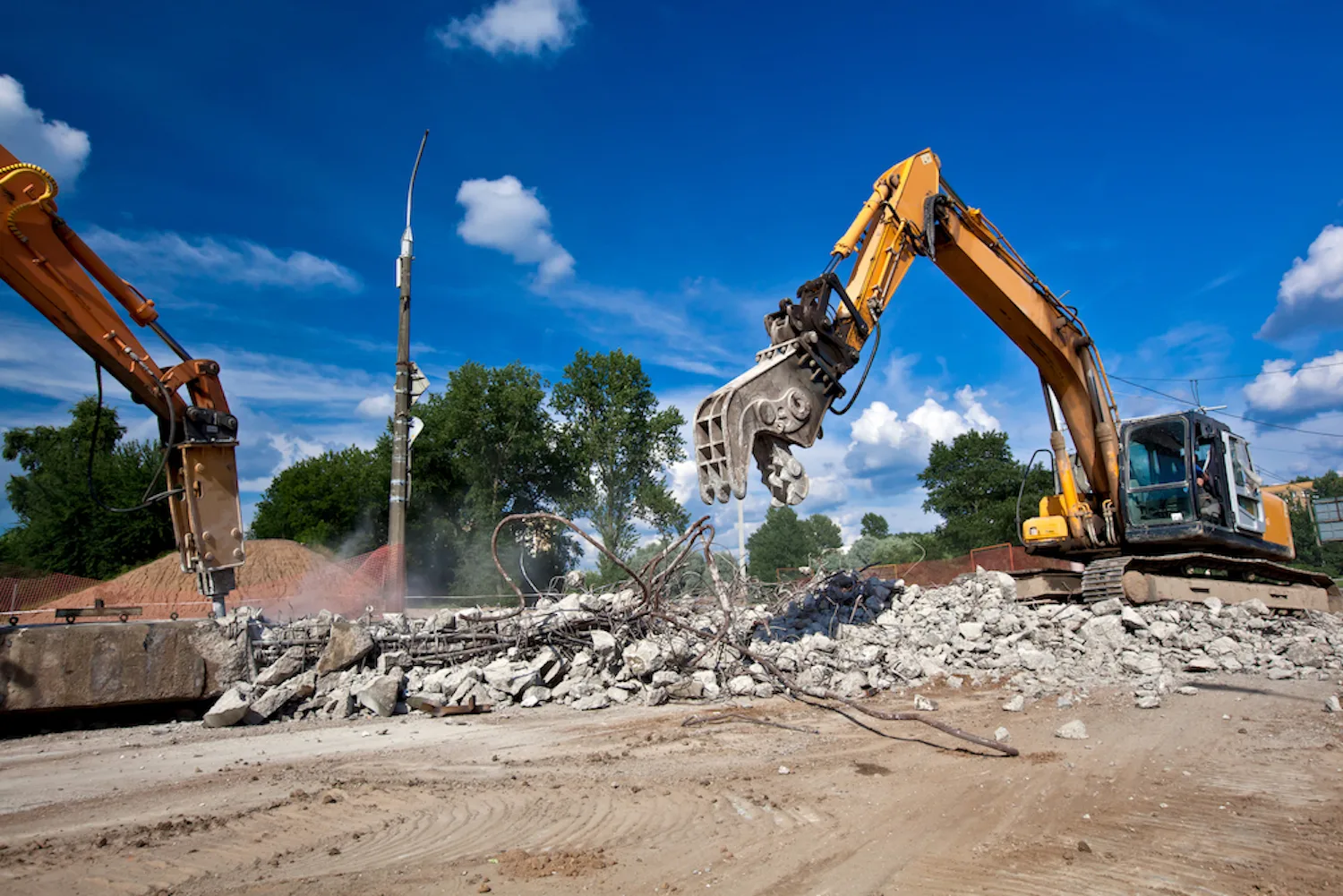Excavator breaking up rubble on a site being cleared