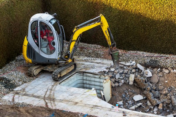 on a private swimming pool construction is dismantled by an excavator